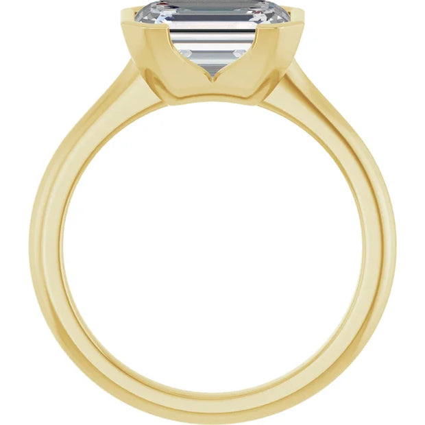 Looking through a 14K yellow gold half bezel engagement ring from the opposite side, showcasing the open space beneath the diamond and the elongated facets of the emerald cut diamond visible through the stone.